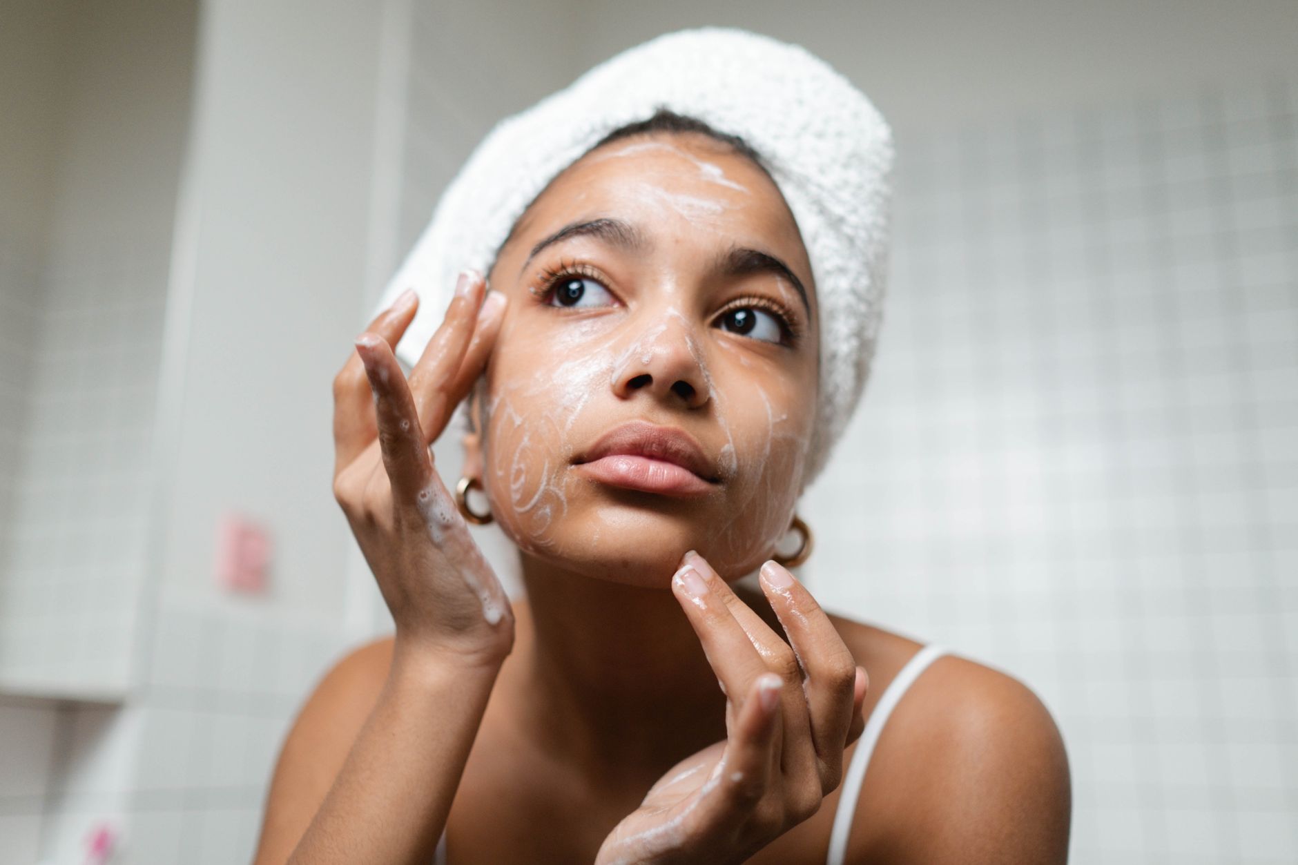 woman in white tank top washing her face with soap
