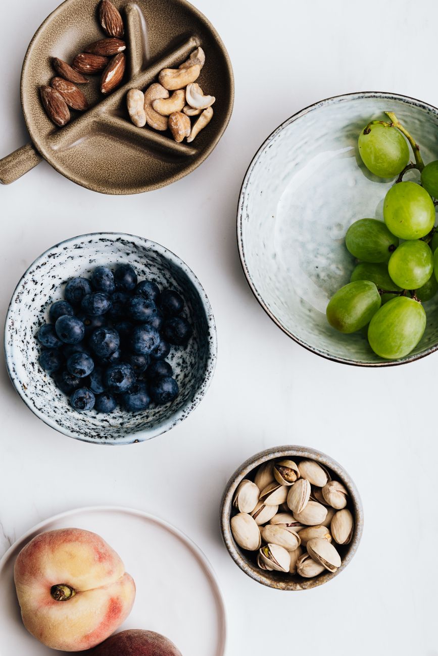 fruits and nuts in plates on white background